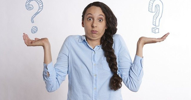 Woman standing, hands up in air, quzzical look on her face