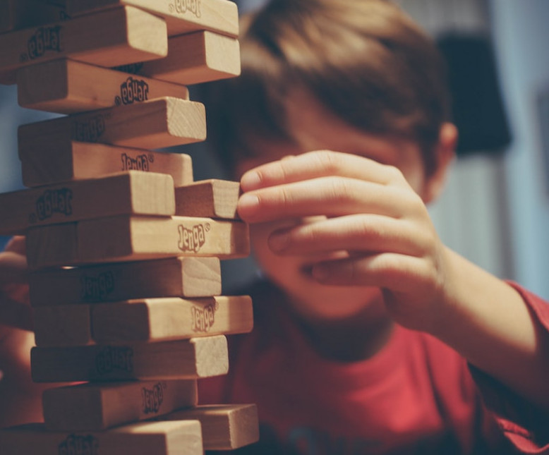 Kid playing a difficult move in Jenga
