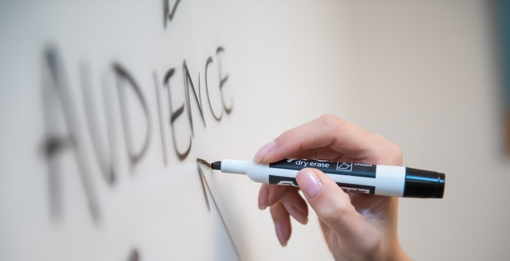 Image is of a hand writing the word audience